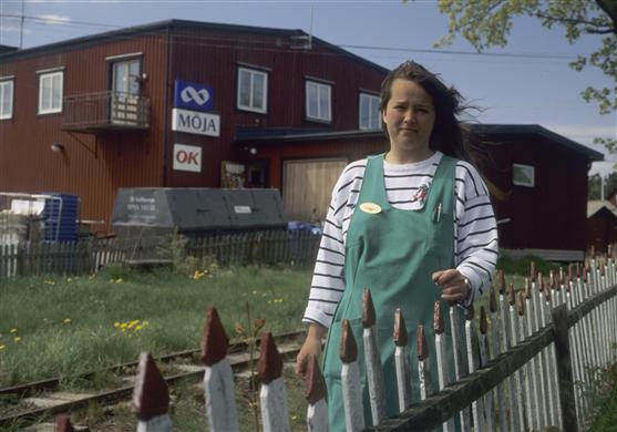 Annika Karlsson framför lanthandeln, där hon arbetar. I bild även räls på järnvägen på Möja.