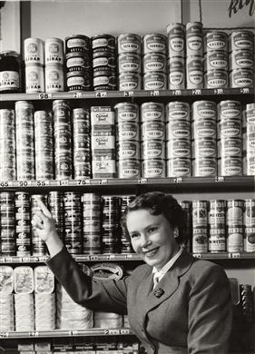 ICA-butik, 1960, husmor kollar i konservhylla med hyllkantsetiketter.