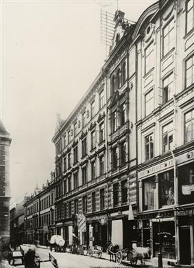 Gatusträcka med exteriör av butiken till höger, samt andra butiker, bl a John Walls järnaffär.
